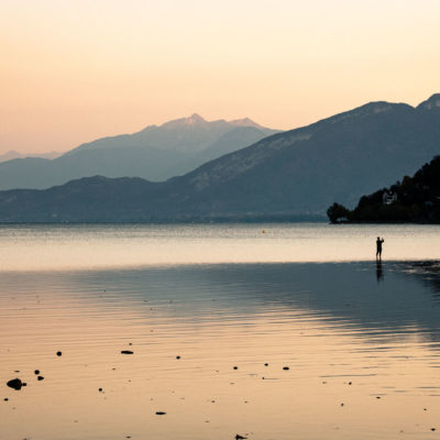 Passant photographiant le faible niveau d'eau du lac d'Annecy