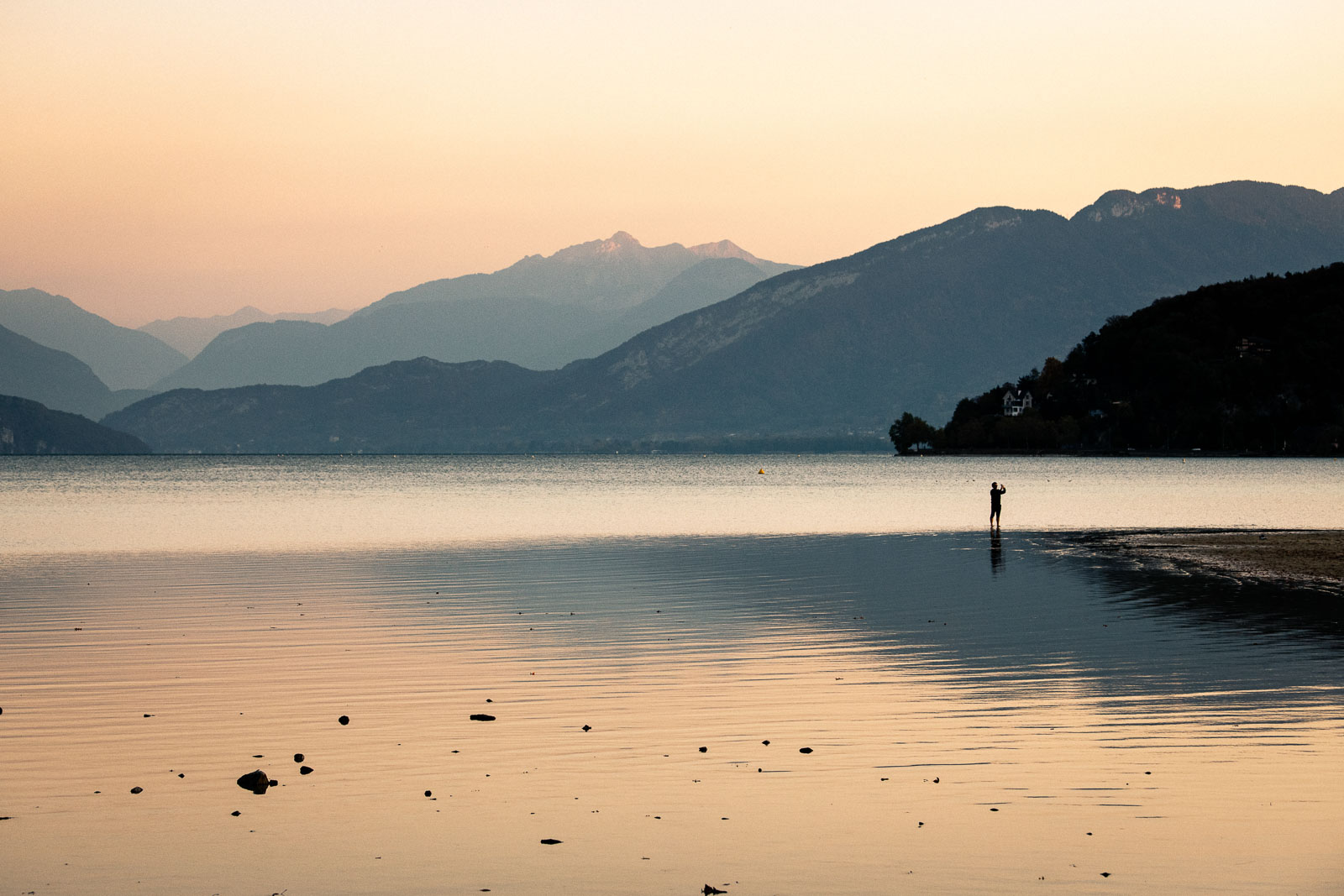 Passant photographiant le faible niveau d'eau du lac d'Annecy