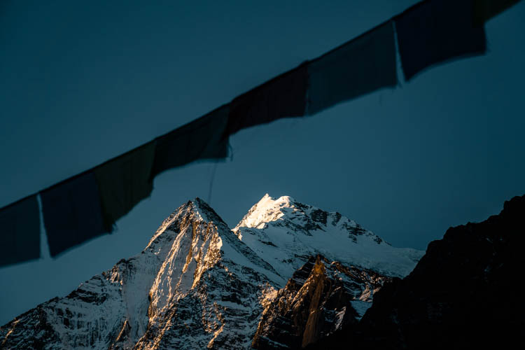 Drapeaux de prière sur fond de soleil couchant, Népal. Format paysage.