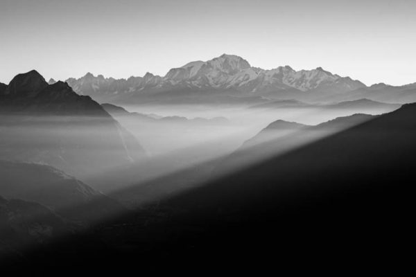 Lumière filtrée sur les vallées alpines face au Mont-Blanc, France. Format paysage.