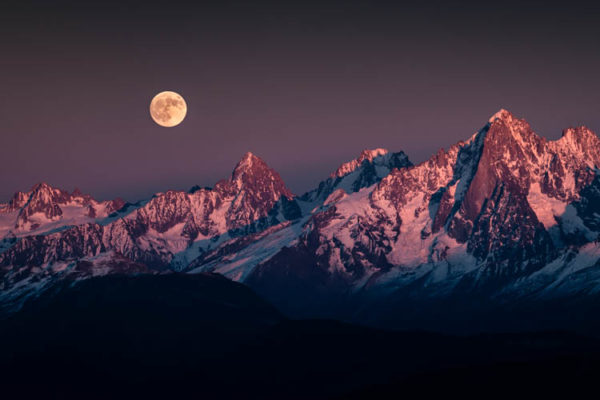 La pleine lune se lève un soir de novembre sur les sommets au Nord du Massif du Mont Blanc, France. Format paysage.