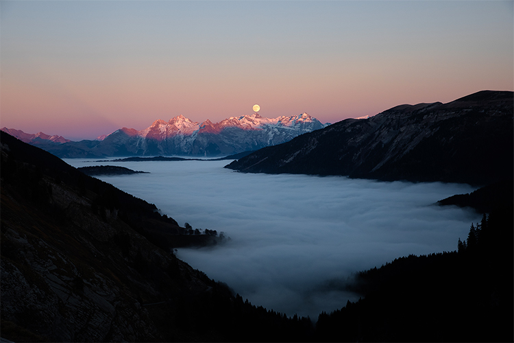 Lever de pleine lune sur une mer de nuages au-dessus de la chaîne des Fiz, France. Format paysage.